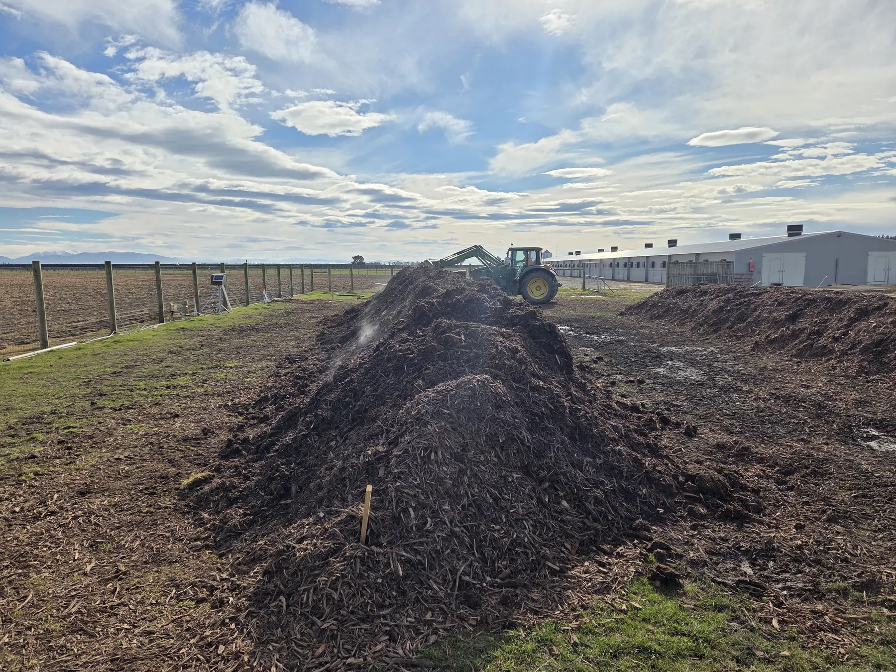 Excavator working alongside long covered compost windrows at Lamond Farm