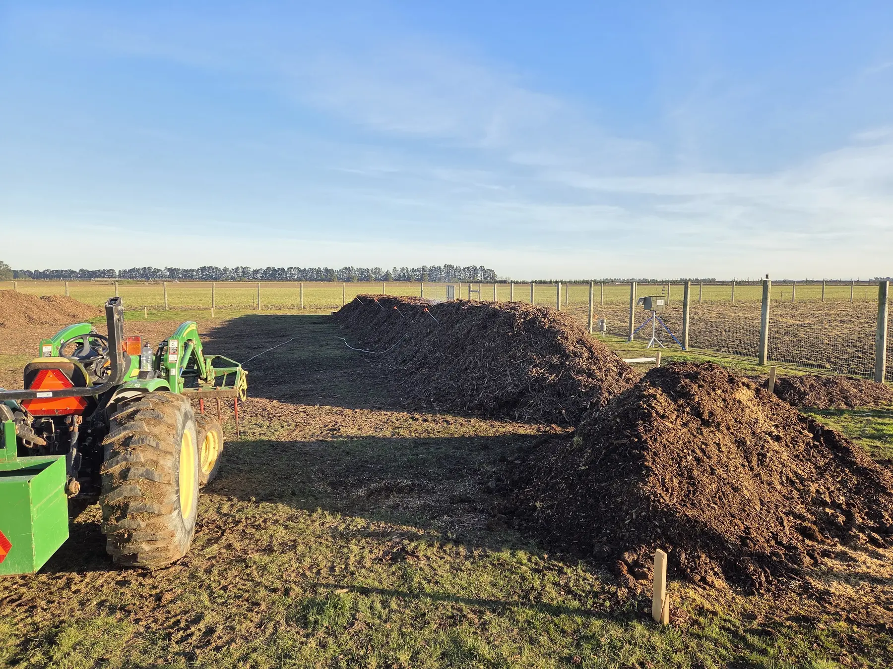 Excavator and multiple long compost windrows showing the scale of the Lamond Farm demonstration