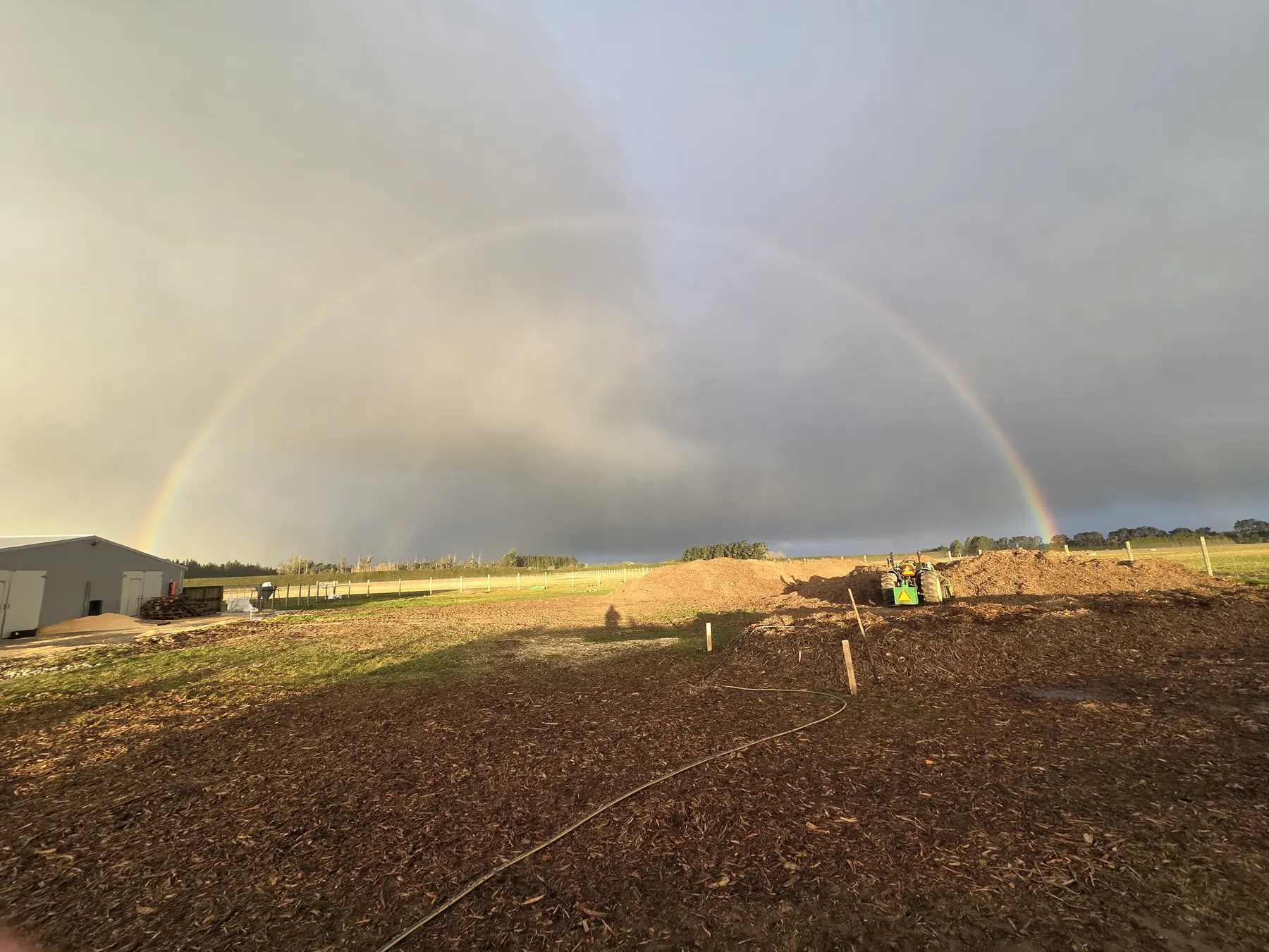 Covered compost windrows beneath a rainbow at Lamond Farm